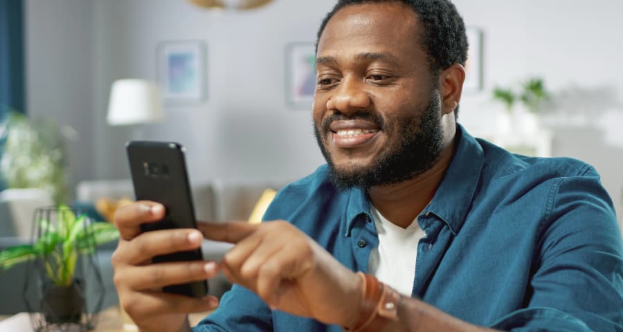 Man in his home using a home security app on his smartphone